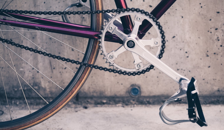 Road bicycle, fixed gear bike on city concrete street. Urban industrial cycling, bike chain on city scene bicycle closeup details, vintage old retro bike, cycling or ecology commuting. Industrial concept.