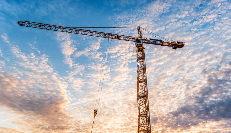 Industrial construction crane with a sunrise in the background.