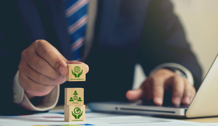 ESG concept of environmental, Businessman hand holding wooden cube block with ESG icon with copy space, Businessman Planing an ESG Project on laptop. Green Energy, Renewable and Sustainable Resources.