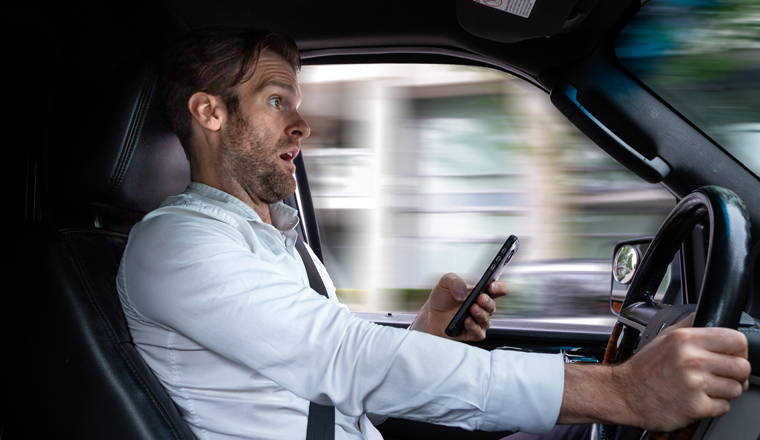 A middle aged caucasian man distracted driving while using a mobile device stops his vehicle suddenly to avoid an accident