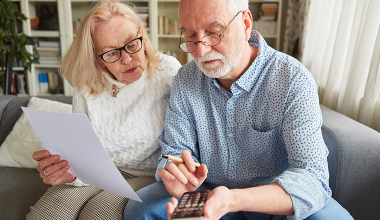 Senioren mit Taschenrechner berechnen Kosten der Finanzierung von Pflege und Altersvorsorge