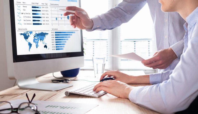Team of financial people discussing a business analytics (BA) or intelligence (BI) dashboard on the computer screen showing sales and operations data statistics and key performance indicators (KPI)