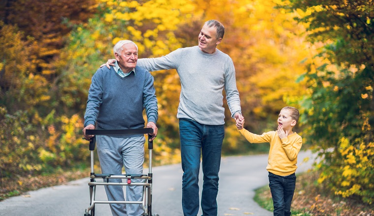 Elderly father adult son and grandson out for a walk in the park.