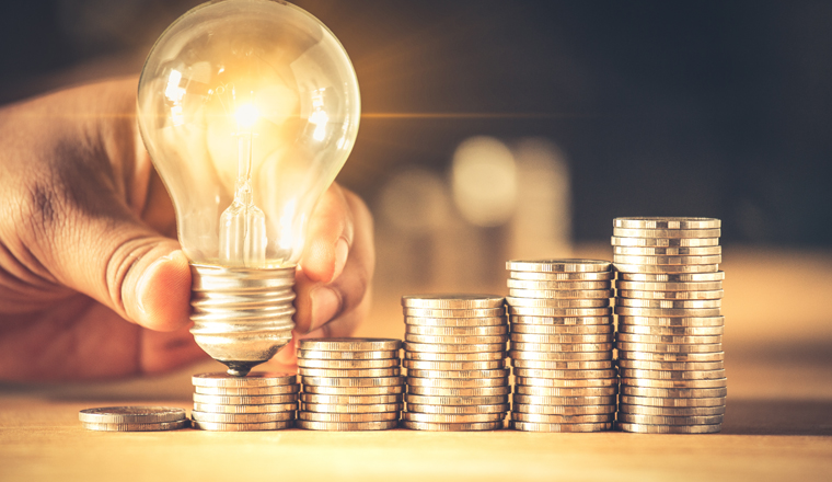 Hand holding a light bulb with coins stack. Creative ideas for saving money concept. Money management for the future