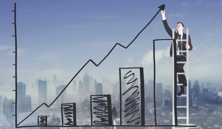 Caucasian businessman drawing an increasing business profit chart against office buildings