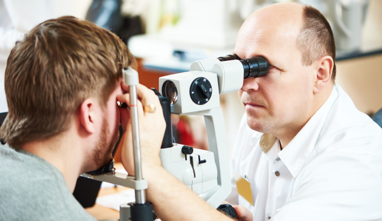Male optometrist optician doctor examines eyesight of female patient in eye ophthalmological clinic