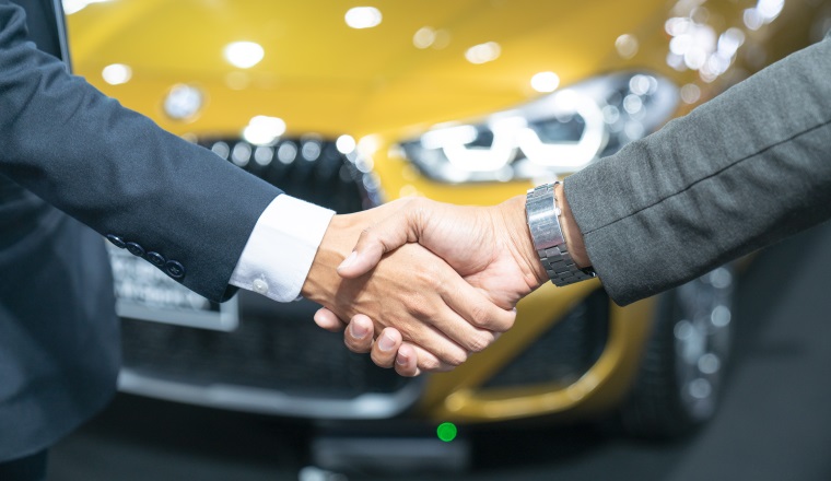 auto business, car sale, deal, gesture and people concept -new owner and shaking hands in auto show or salon