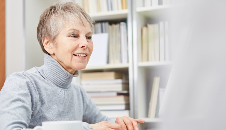 Seniorin arbeitet aufmerksam am Computer online im Cyberspace