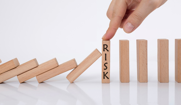 domino effect and risk management concept. manager stops falling wooden cubes with his finger.