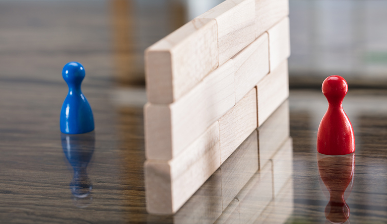 Close-up Of Red And Blue Figurine Paw Separated By Wooden Blocks On Desk