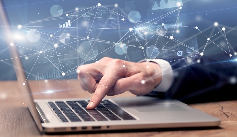 Businessman typing on laptop with linked reports charts grapghs around
