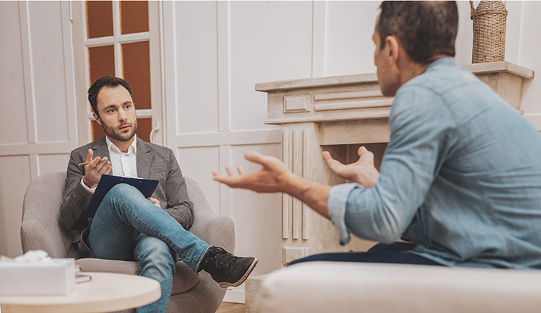 Qualified therapist. Dark-eyed qualified therapist wearing stylish grey jacket giving needed treatment to his anxious client