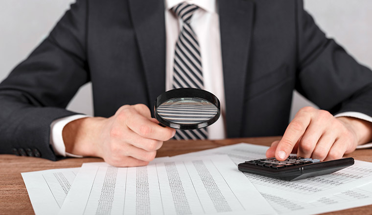 Businessman holding magnifying glass zoom and looking to financial statement