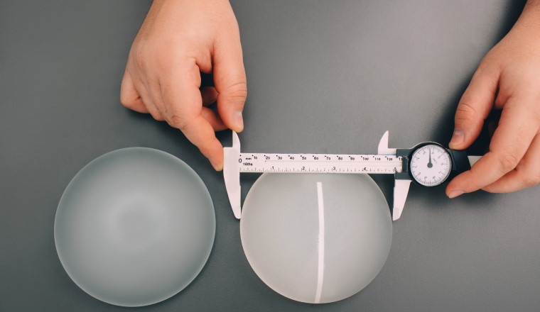Surgeon measure size silicone breast implants, close-up, view from above. Cosmetic breast surgery.