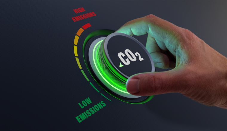 Lower CO2 emissions to limit global warming and climate change. Concept with manager hand turning knob to reduce levels of CO2. New technology to decarbonize industry, energy and transport