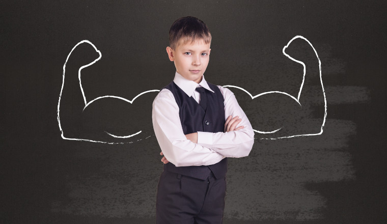 Little boy with drawn powerful hands. Black chalkboard background.