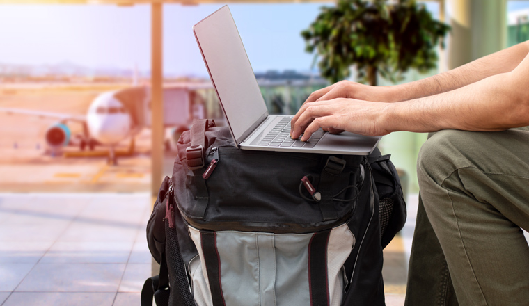 Cropped shot of an unrecognizable digital nomad sitting alone and typing on his laptop during the day at airport