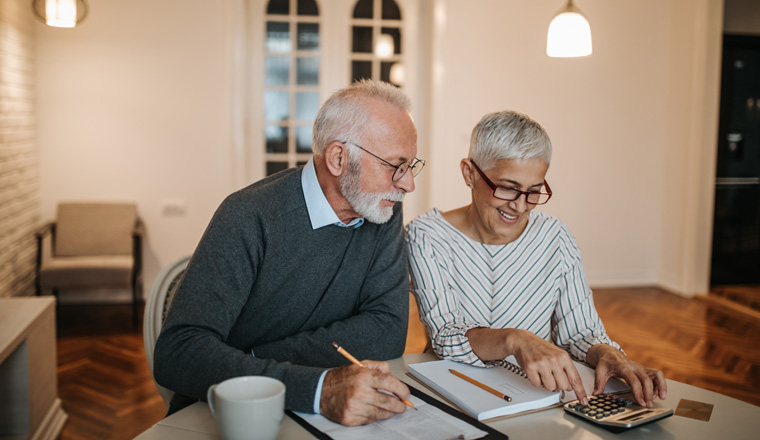 A happy senior couple calculating their finances in a beautiful home.