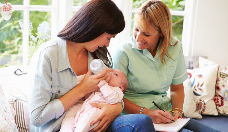 Mother With Baby Meeting With Health Visitor At Home