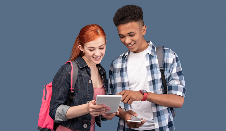 Modern technology. Happy young people standing together while using a tablet