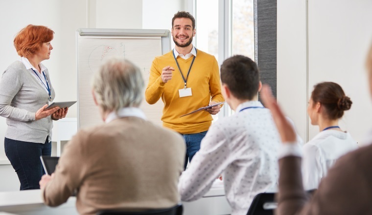 Business Team im Consulting Seminar diskutiert mit dem Berater oder Dozenten