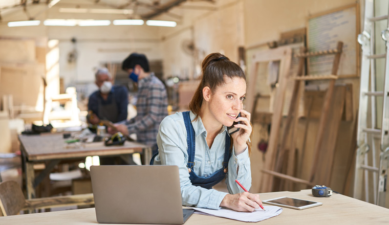 Handwerker Frau bei Kundengespräch am Telefon in einer Schreinerei Werkstatt