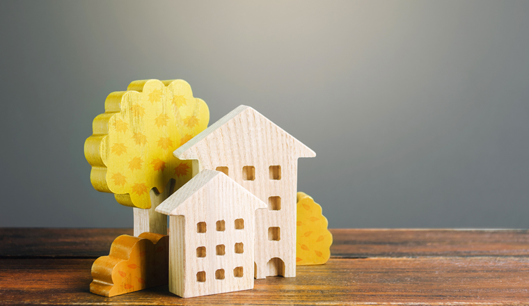 Wooden figurines of residential buildings and autumn yellow trees. Buying or renting a house. Sale offers of real estate. Affordable comfortable housing. Mortgage. Interpretation of the autumn city