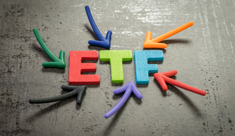 ETF, exchange-traded fund an investment fund traded on stock exchanges concept, multi color arrows pointing to the word ETF at the center of black cement chalkboard wall.