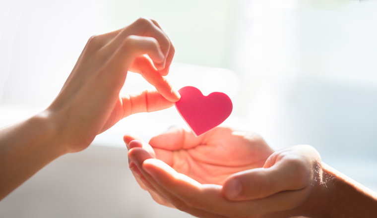 Close-up Of Woman Giving Red Heart On Man's Hand