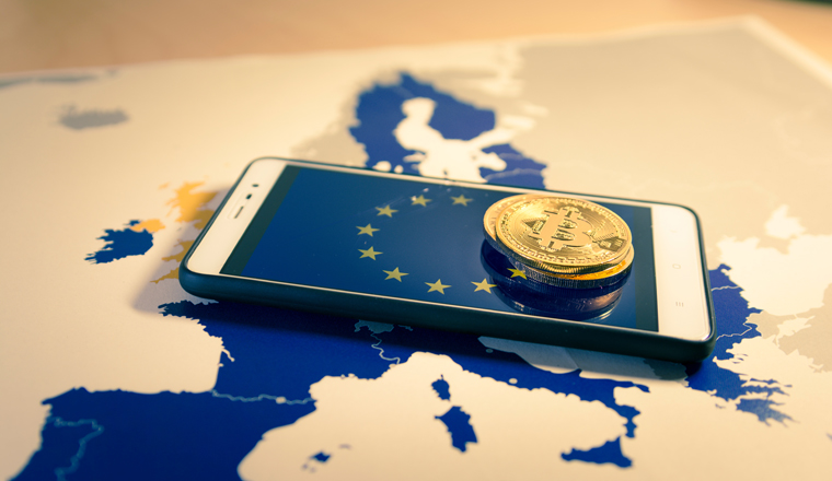 Financial concept with golden Bitcoin over smartphone, UE flag and map. Situation of Bitcoin and other cryptocurrencies in European Union concept. Warm mood