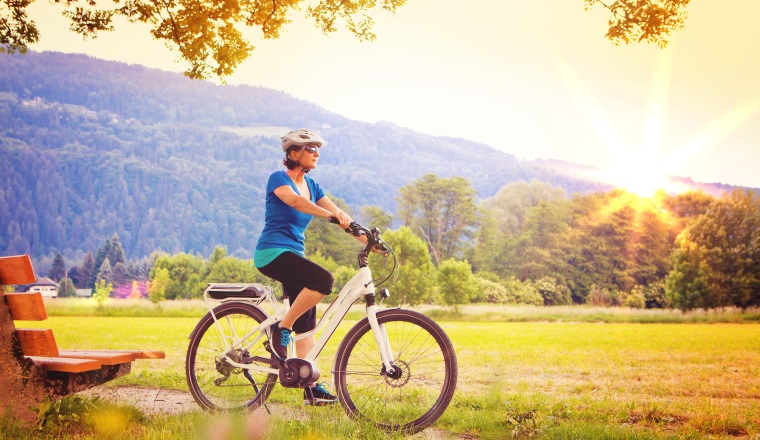 Happy senior man standing talking at mobile phone. Aluminum background. One caucasian people. Using e bike with helmet