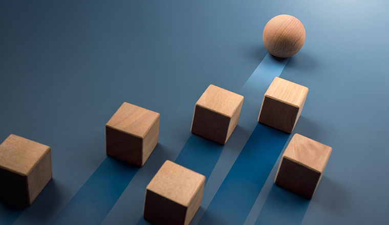 Leadership, business success, unique, difference, challenge, and motivation concepts creative ideas. Wooden sphere rolling faster leading first and following with wood cube blocks on blue background.