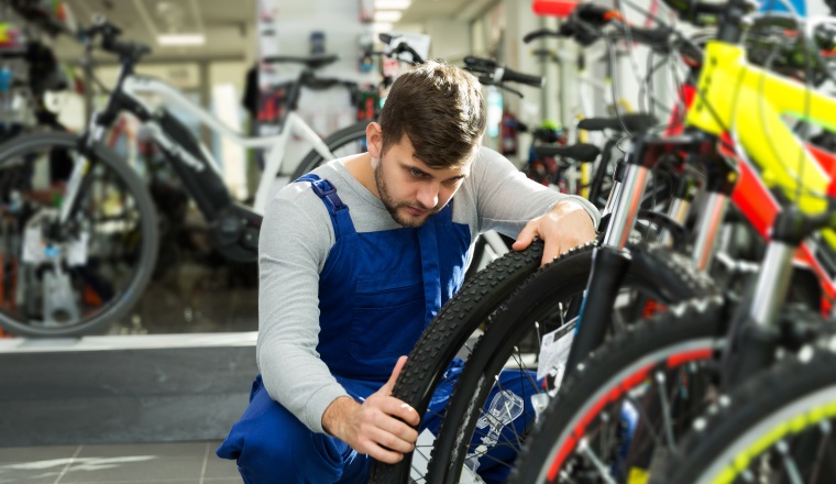 Portrait of professional man checking tire on wheel in bicycle shop