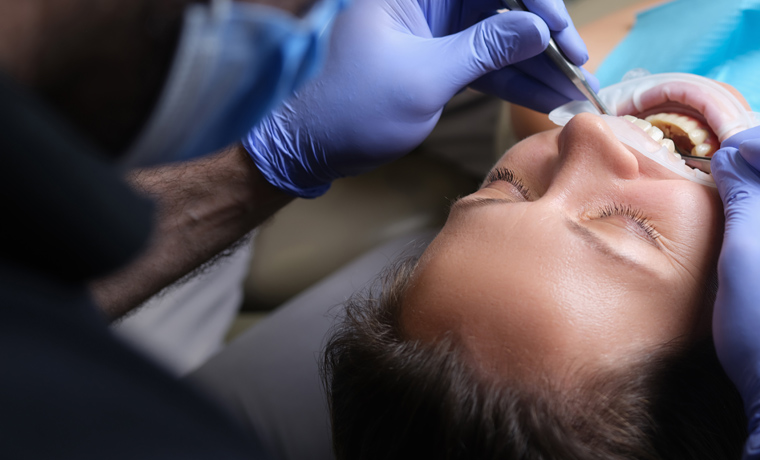 Dentist treats teeth with caries to female patient in dental clinic. Care and treatment of teeth concept