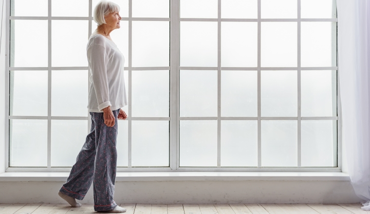 Smiling pensioner in pajama going in hospital apartment near window