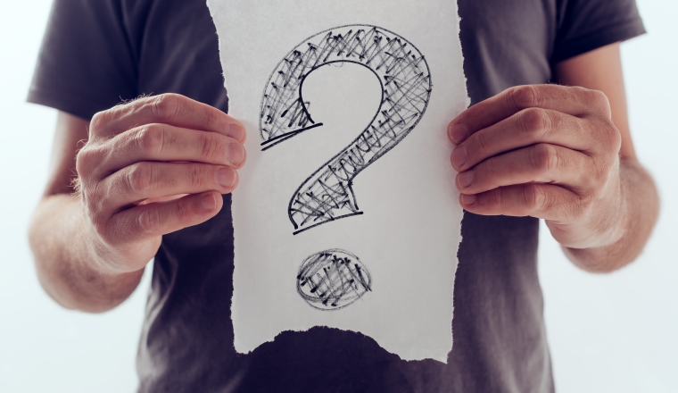 Question mark, looking for answers. Man holding paper with scribbled interrogation point, query, or eroteme punctuation