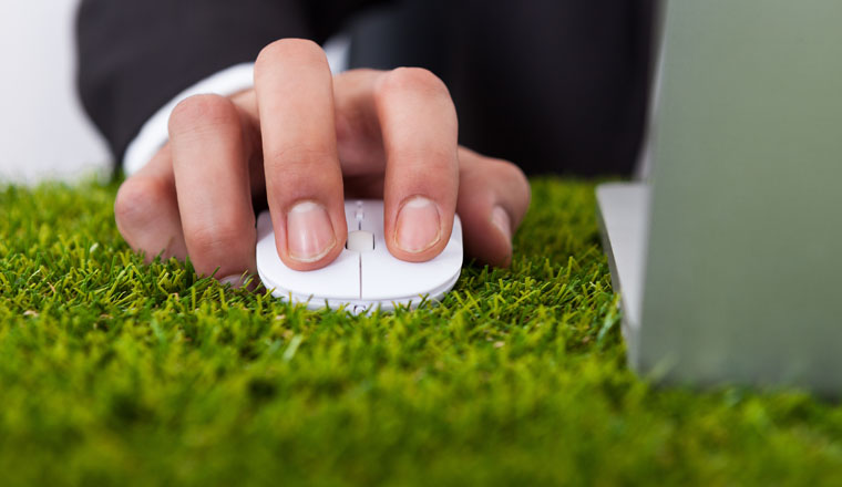 Midsection of businessman using laptop with computer mouse on grass