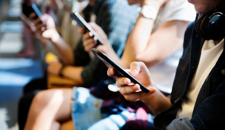 Group of young adult friends using smartphones in the subway