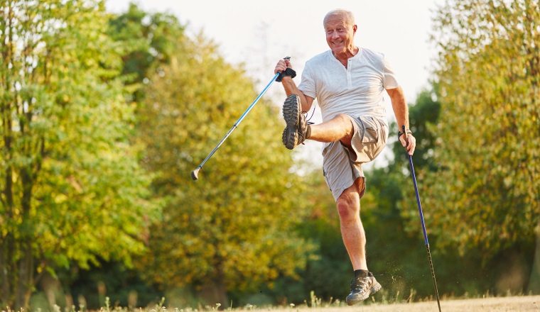 Senior hat Spaß und albert herum beim Nordic Walking im Park