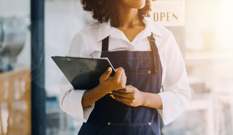 Startup successful small business owner sme beauty girl stand with tablet smartphone in coffee shop restaurant. Portrait of asian tan woman barista cafe owner. SME entrepreneur seller business concept