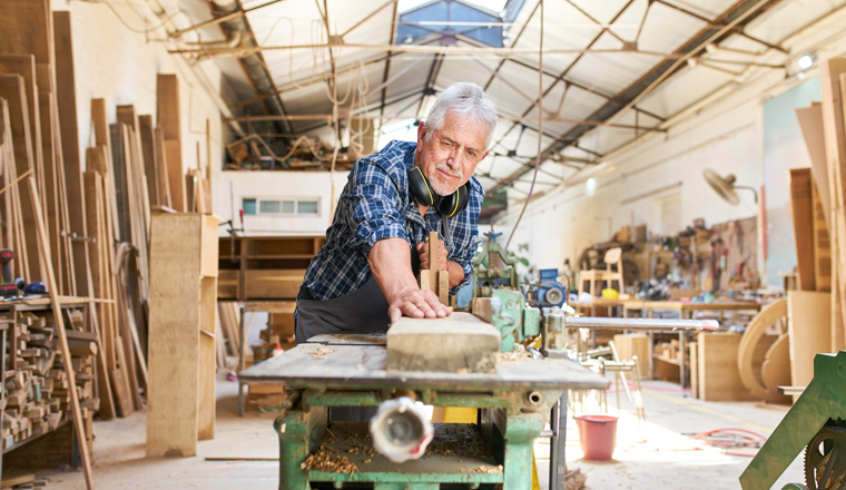 Senior Handwerker arbeitet an der Hobelmaschine in der Werkstatt der Tischlerei