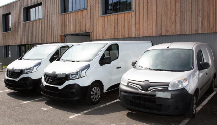 Three White Delivery Trucks vans Backed Up to Warehouse Building