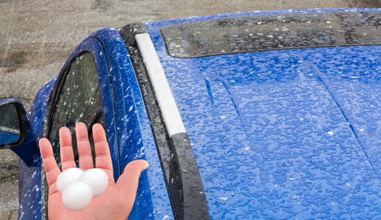 Hagel f??llt auf ein blaues Auto Dach.