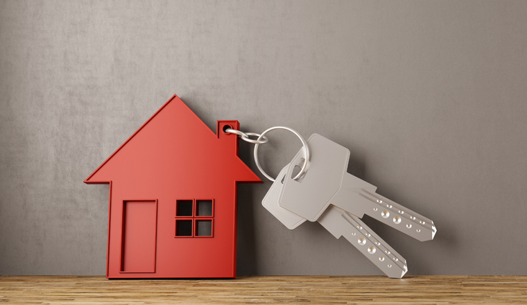 Schlüssel mit Haus an Wand gelehnt als Symbol für Hausfinanzierung