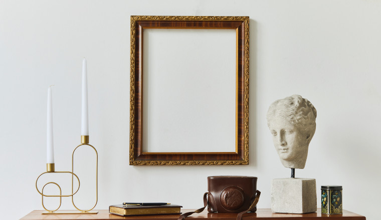 Stylish composition of artist workspace room with design retro teak commode, mock up poster frame, book, decoration and elegant accessories. Template.