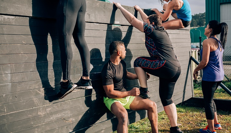 Group of participants in an obstacle course climbing a wall