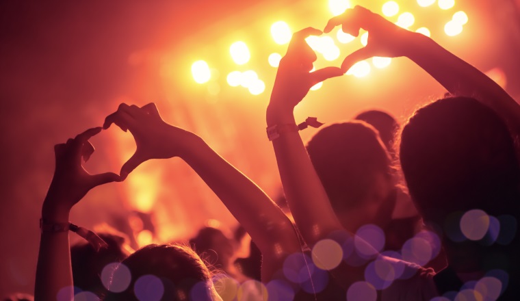 Cheering crowd in front of bright colorful stage lights.