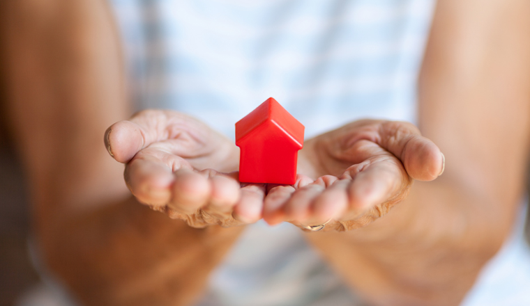 Elderly woman holding a small house in her hands