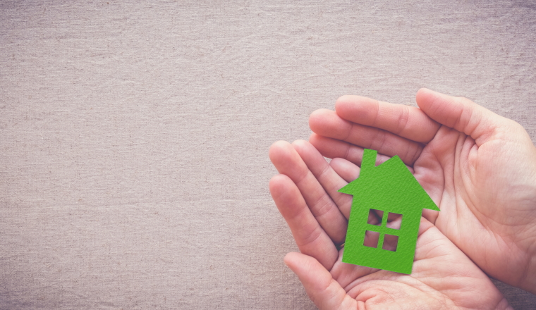 hands holding green paper house, eco house concept