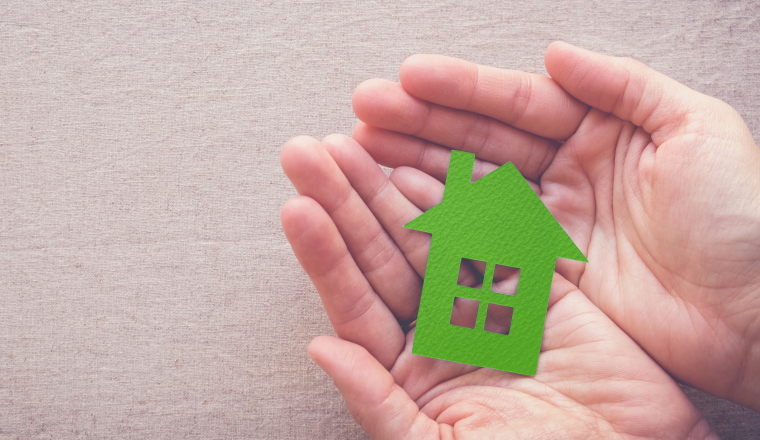 hands holding green paper house, eco house concept